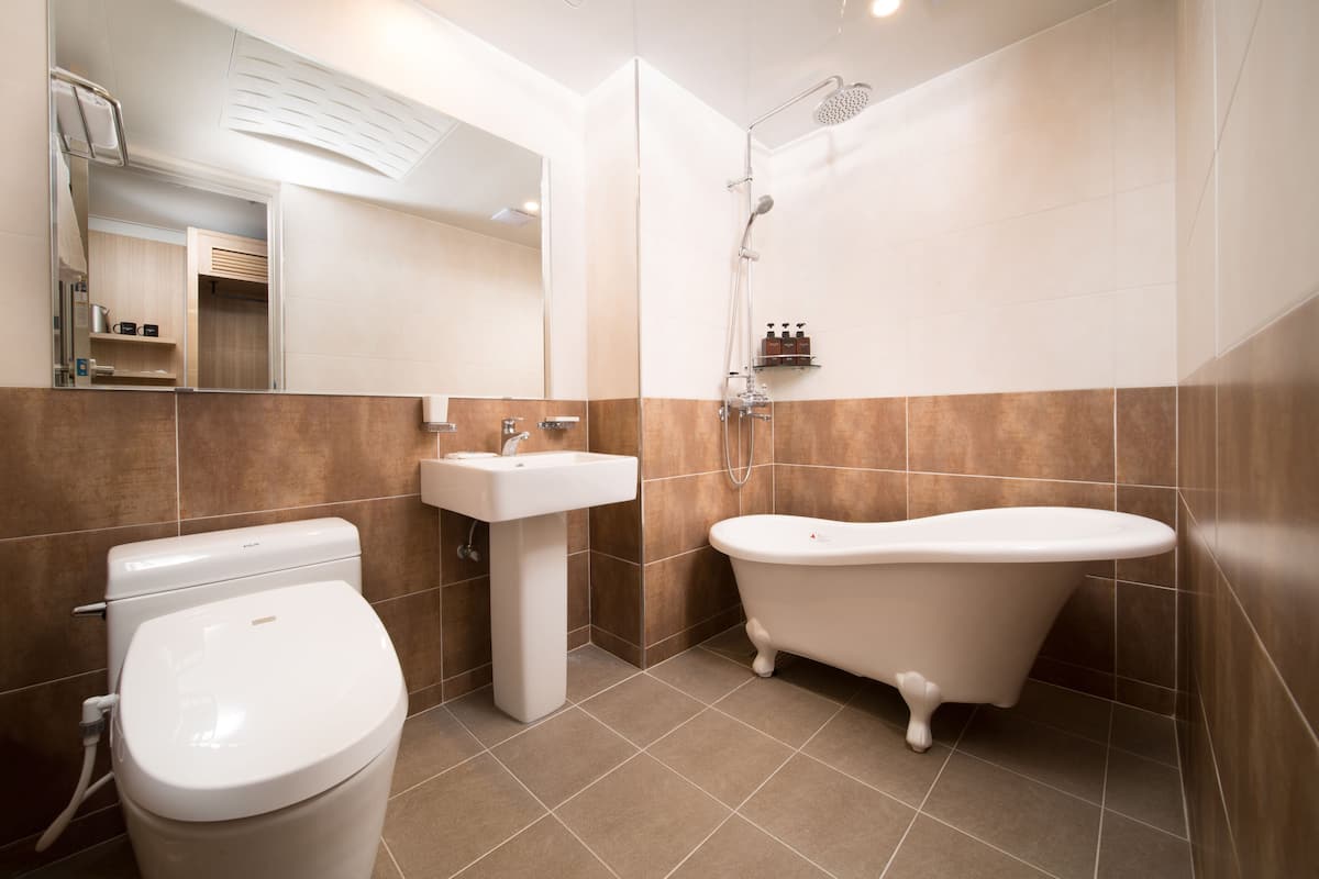 A modern bathroom with a toilet, sink, and freestanding bathtub.