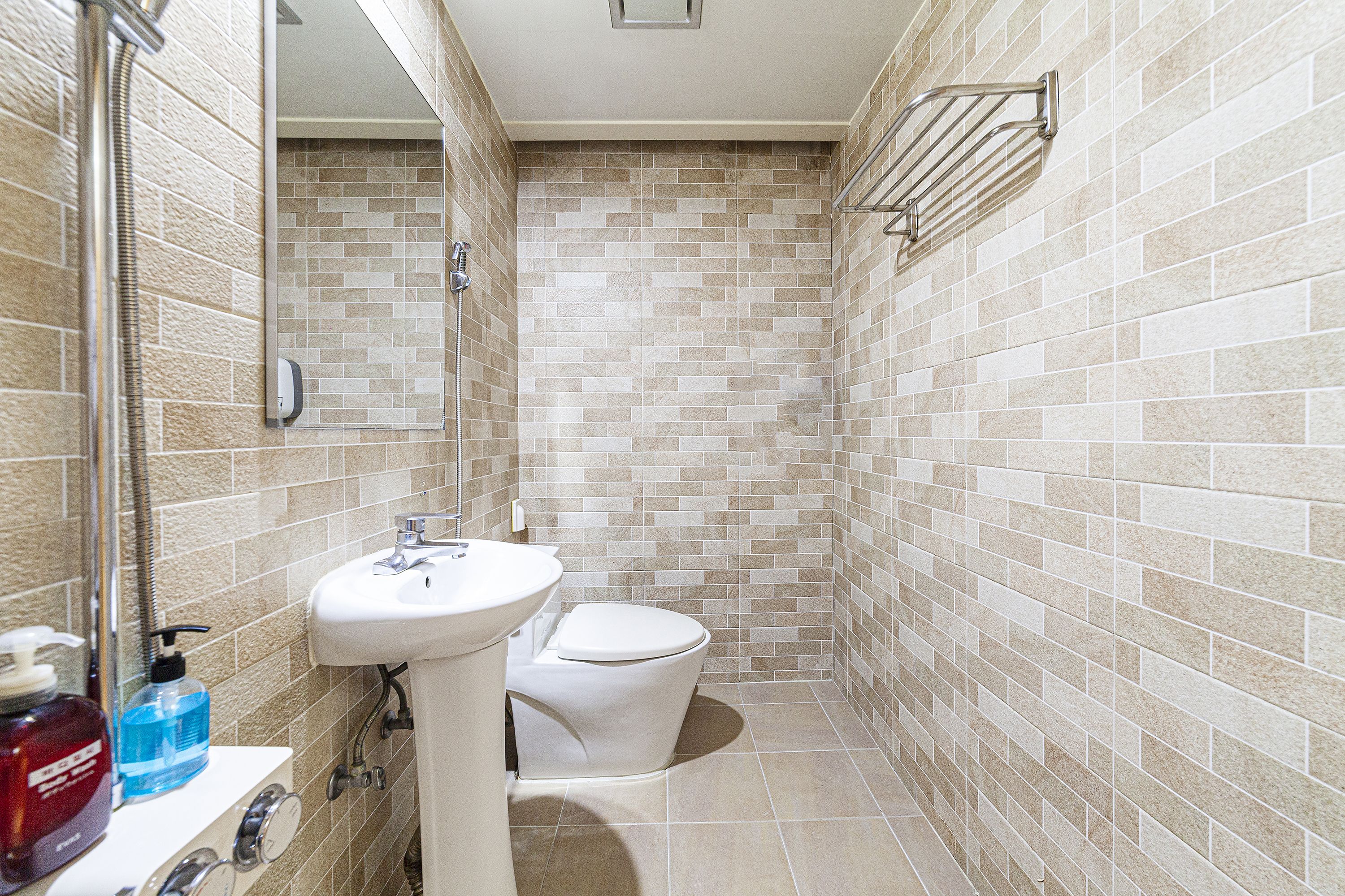 Un baño con lavamanos, inodoro y paredes revestidas con azulejos.