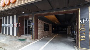 A hotel entrance with a brick facade, a sign for a nearby cinema, and a parking symbol. - Busan station Popcorn Hotel (Busan)
