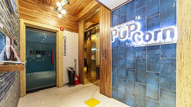A hotel lobby with a wooden ceiling, a sign for 'Popcorn', and a fire extinguisher. - Busan station Popcorn Hotel (Busan)