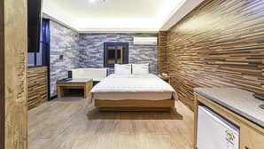 A modern hotel room with a bed, bedside tables, a small desk, and a built-in refrigerator. - Busan station Popcorn Hotel (Busan)