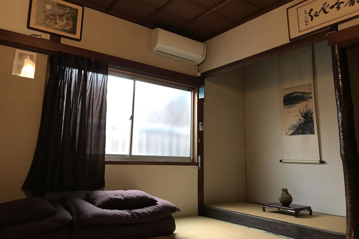 A traditional Japanese room with tatami flooring, a sliding door, and a small table with a vase.