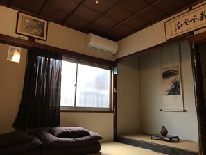 A traditional Japanese room with tatami flooring, a sliding door, and a small table with a vase. - SUGIYA Guest House - Hostel (Nara)