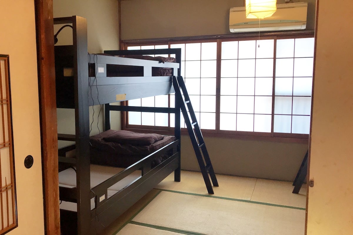 A bunk bed room with a ladder, a window with a view, and a radiator.