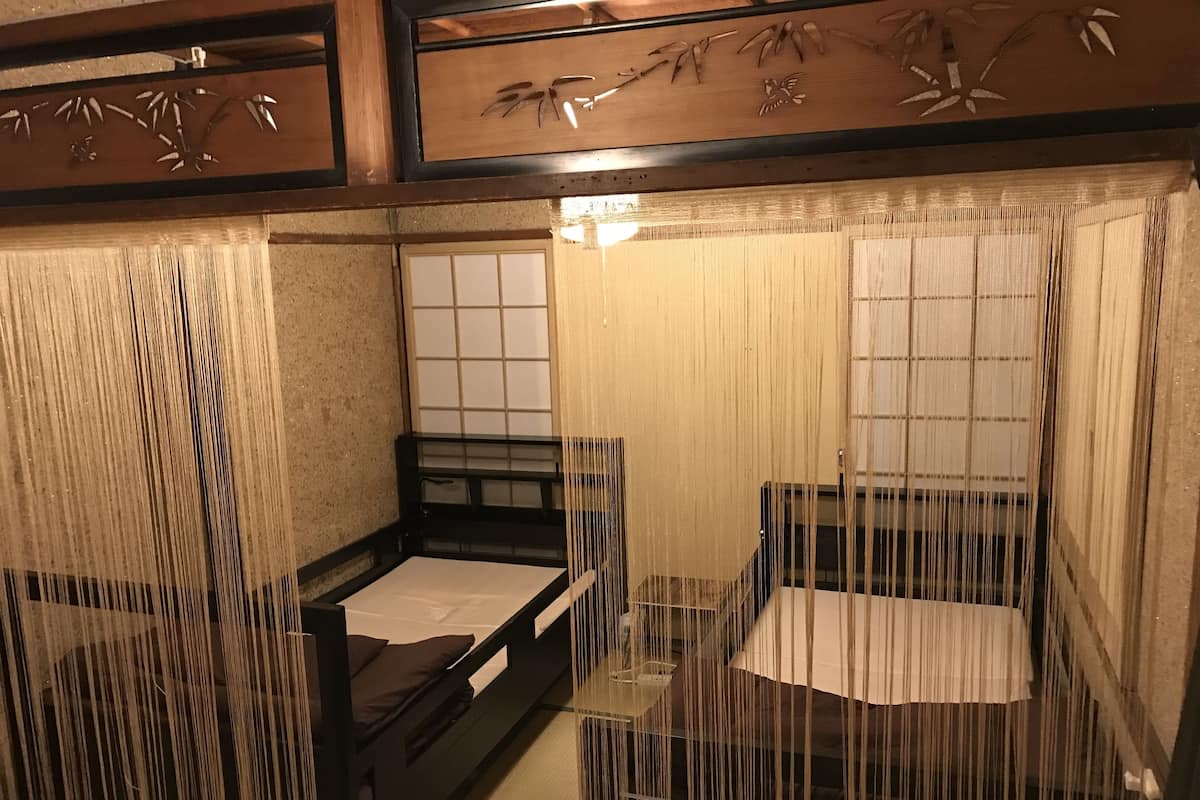 A traditional Japanese-style room with tatami flooring, sliding doors, and a low wooden bed.