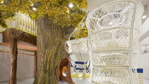 A treehouse play area with a rope ladder, a wooden bench, and a white woven chair. - Grand Bay Hotel Beijing (Miyun)
