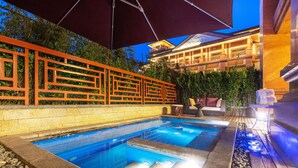A swimming pool with a wooden deck and a red fence. - Grand Bay Hotel Beijing (Miyun)