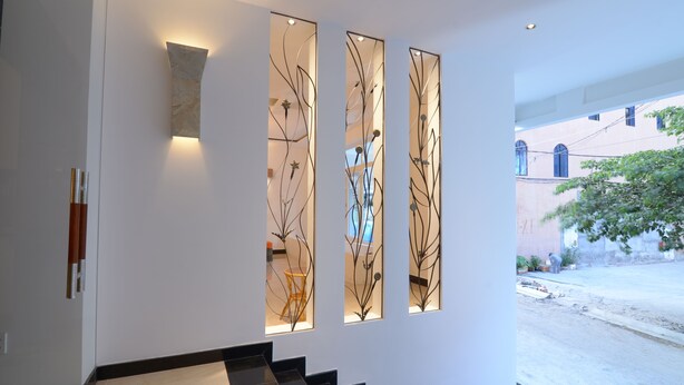 A modern interior with a staircase, decorative wall panels, and a view of the outside. - Veevoo Hotel (Ho Chi Minh City)