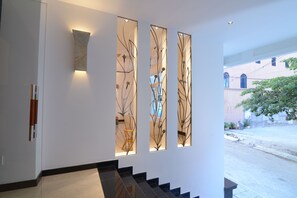A modern interior with a staircase, decorative wall panels, and a view of the outside. - Veevoo Hotel (Ho Chi Minh City)