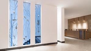A modern hotel lobby with a reception desk, a decorative wall with abstract designs, and a polished marble floor. - Veevoo Hotel (Ho Chi Minh City)