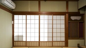 A traditional Japanese room with tatami flooring, sliding shoji doors, and a built-in air conditioning unit. - Guest House Route53 Furuichi (Nara)