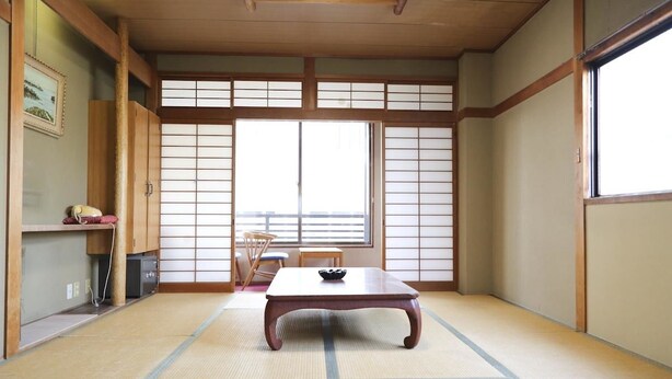 A traditional Japanese room with tatami flooring, a low wooden table, sliding shoji doors, and a view through a large window. - Guest House Route53 Furuichi (Nara)