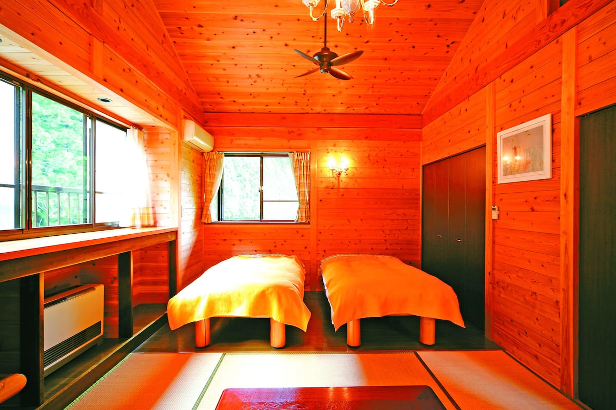Eine Hütte mit zwei Betten, einem Schreibtisch, einem Fenster und einem Deckenventilator.