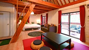 Una habitación con escalera de madera, cama, sofá, mesa y vistas al exterior.