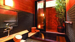 Un baño moderno con detalles de madera, un espejo grande, un lavamanos, un inodoro y una planta en maceta.