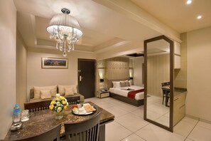 A hotel room with a dining area, a bed, a bathroom, and a large mirror. - The Baroda Residency (Vadodara)