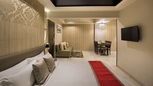 Ein modernes Hotelzimmer mit einem großen Bett, einer Couch, einem Essbereich und einem Fernseher.