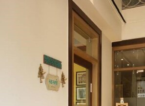 A hotel entrance with a wooden door, a glass window, and a sign with a green border.