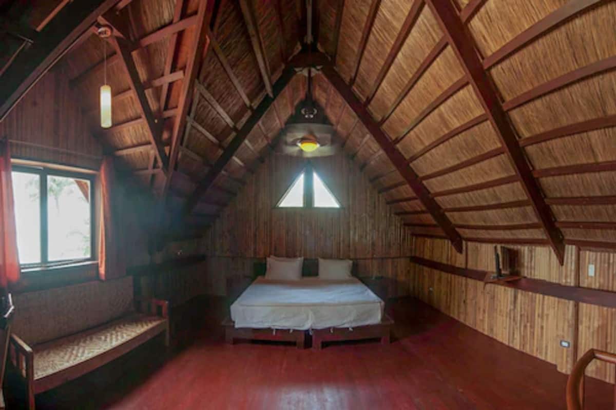 Ein Zimmer mit Holzboden, einem Bett, einer Bank und einem Fenster.
