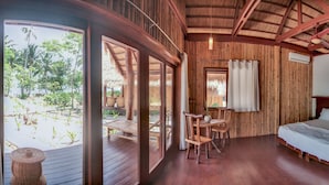 A wooden room with a bed, a table, and chairs. - QI Palawan by Cocotel powered by ASTON (El Nido)