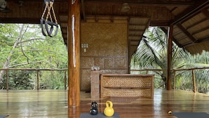 A spacious room with a wooden floor, a reception desk, and exercise equipment. - QI Palawan by Cocotel powered by ASTON (El Nido)