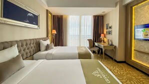 A hotel room with two beds, a desk, and a TV. - Grand Keisha Yogyakarta (Depok)