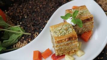 A white plate with a layered pastry, mint leaves, and diced fruits.