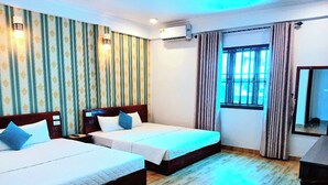 A hotel room with two beds, a wooden floor, striped wallpaper, an air conditioning unit, a window with curtains, and a mirror. - Coto Dream Hotel (Co To)