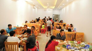 A dining area with wooden tables and chairs, multiple dining sections, and ceiling fans. - Coto Dream Hotel (Co To)