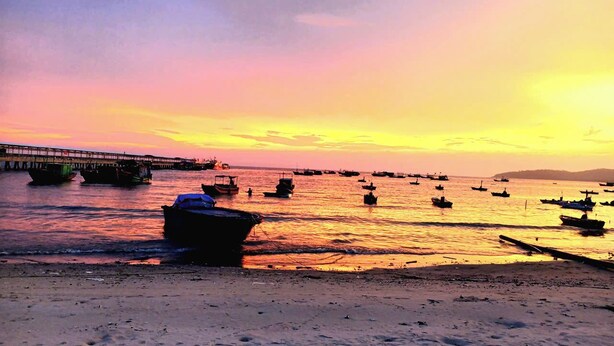 A beach with boats and a pier during sunset. - Coto Dream Hotel (Co To)
