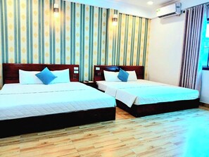 Une chambre d’hôtel avec deux lits, un papier peint à rayures, un plancher en bois et un appareil de climatisation.