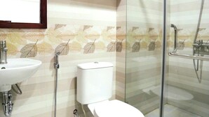 A bathroom with a sink, toilet, and glass-enclosed shower area. - Coto Dream Hotel (Co To)