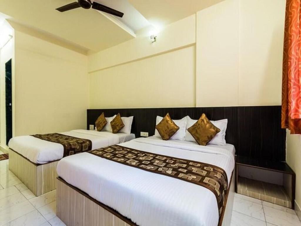 A hotel room with two beds, a ceiling fan, and a nightstand.