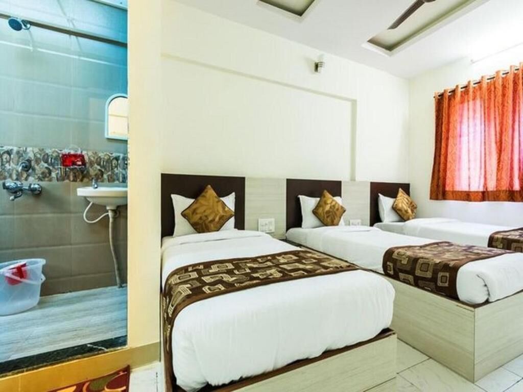 Une chambre d’hôtel avec trois lits, un espace douche et une fenêtre avec des rideaux.