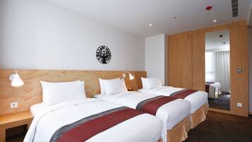 A hotel room with two beds, wooden headboards, white bedding, and a mirror on one wall.