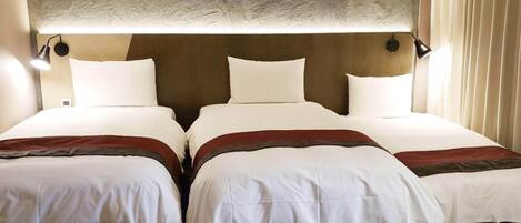 A hotel room with two beds, each with white bedding and a brown accent.
