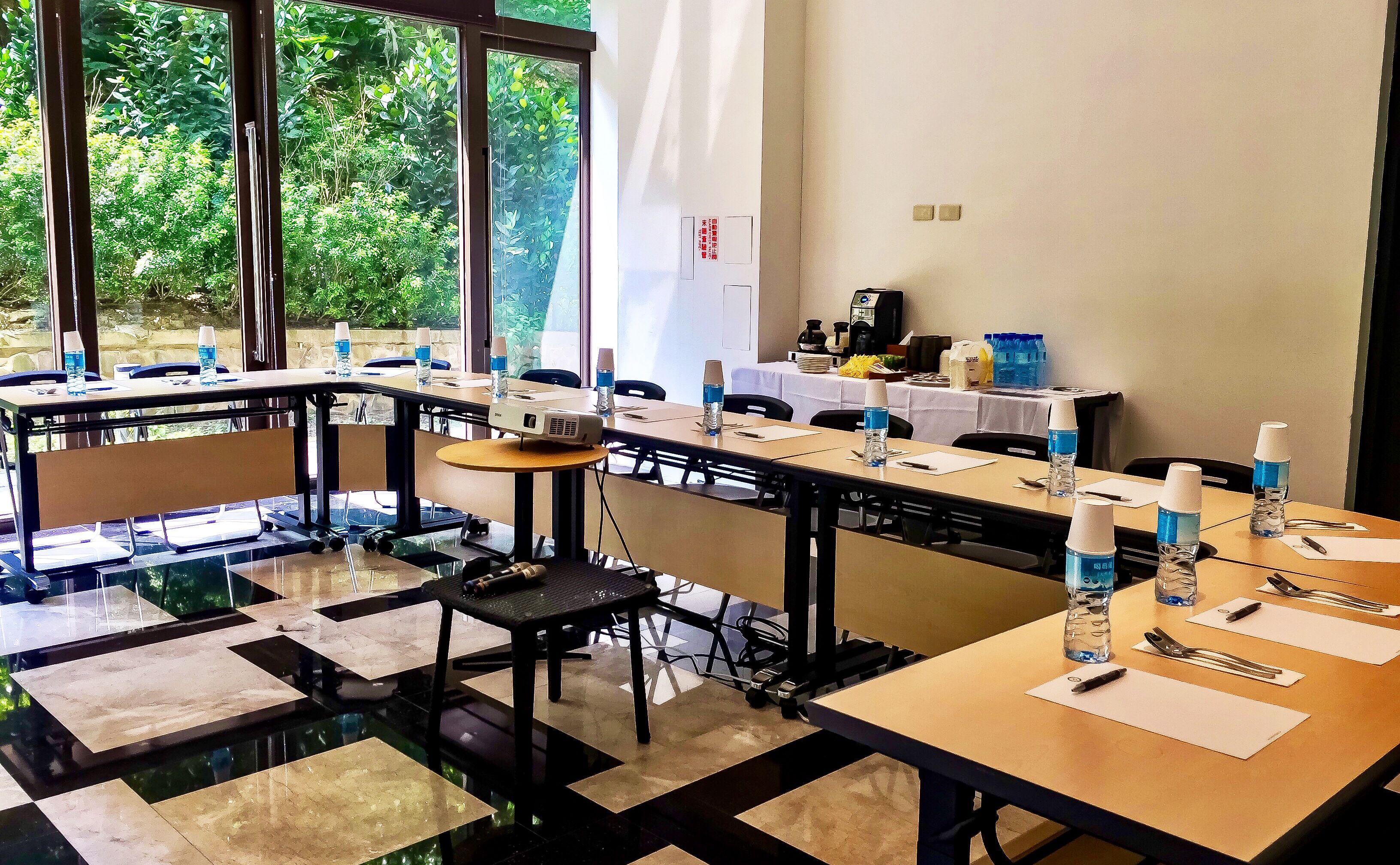 A conference room with tables set for a meeting, equipped with water bottles, notepads, and pens.