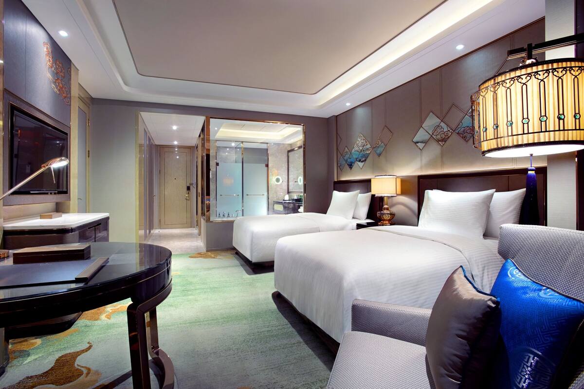 Una habitación de hotel con cama, escritorio, silla, televisor y baño.