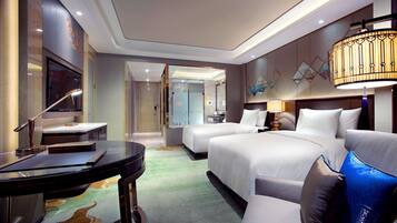 A hotel room with a bed, a desk, a chair, a TV, and a bathroom.