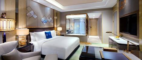 A hotel room with a large bed, two bedside tables, a TV, a sofa, and a desk.