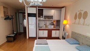 A compact hotel room with a bed, bedside lamp, and a kitchenette. - Hongstay in Hongdae (Seoul)