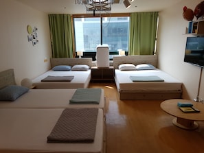 A hotel room with two beds, a desk, a chair, a TV, and a window with curtains. - Hongstay in Hongdae (Seoul)