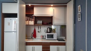 A compact kitchen with a refrigerator, microwave, and a small countertop. - Hongstay in Hongdae (Seoul)