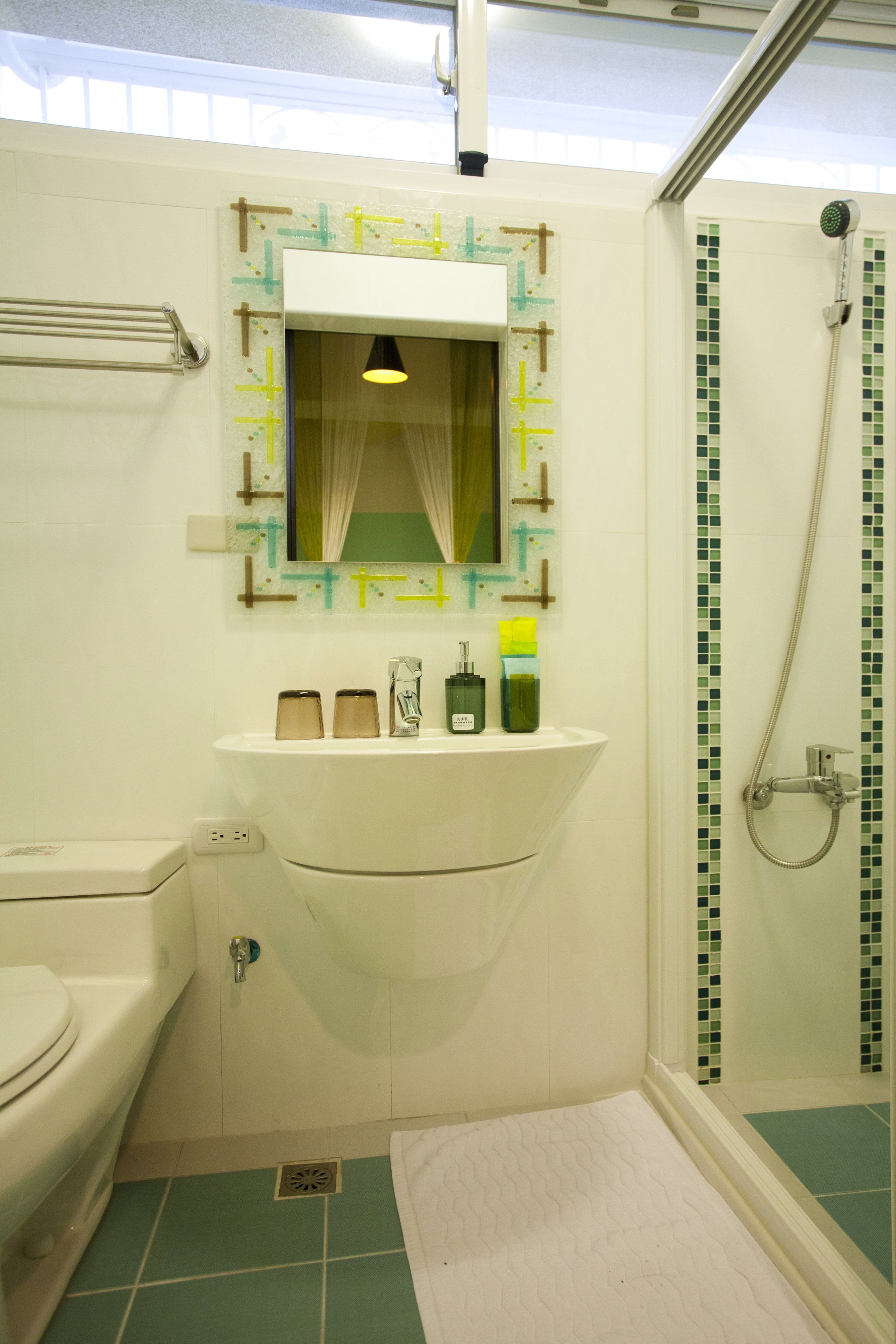 A bathroom with a sink, mirror, and shower.