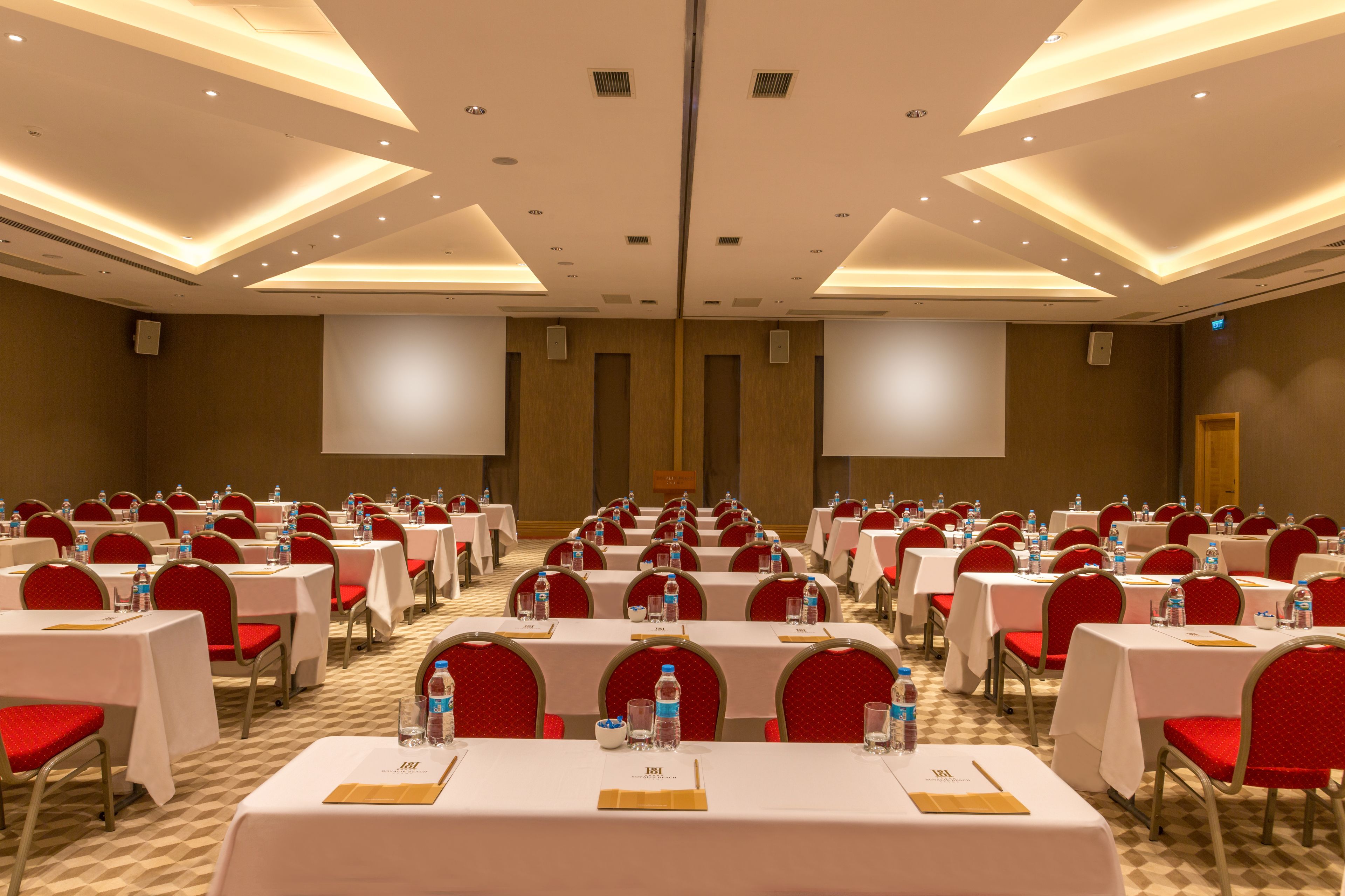 A conference room with rows of tables and chairs, equipped with water bottles and name cards.