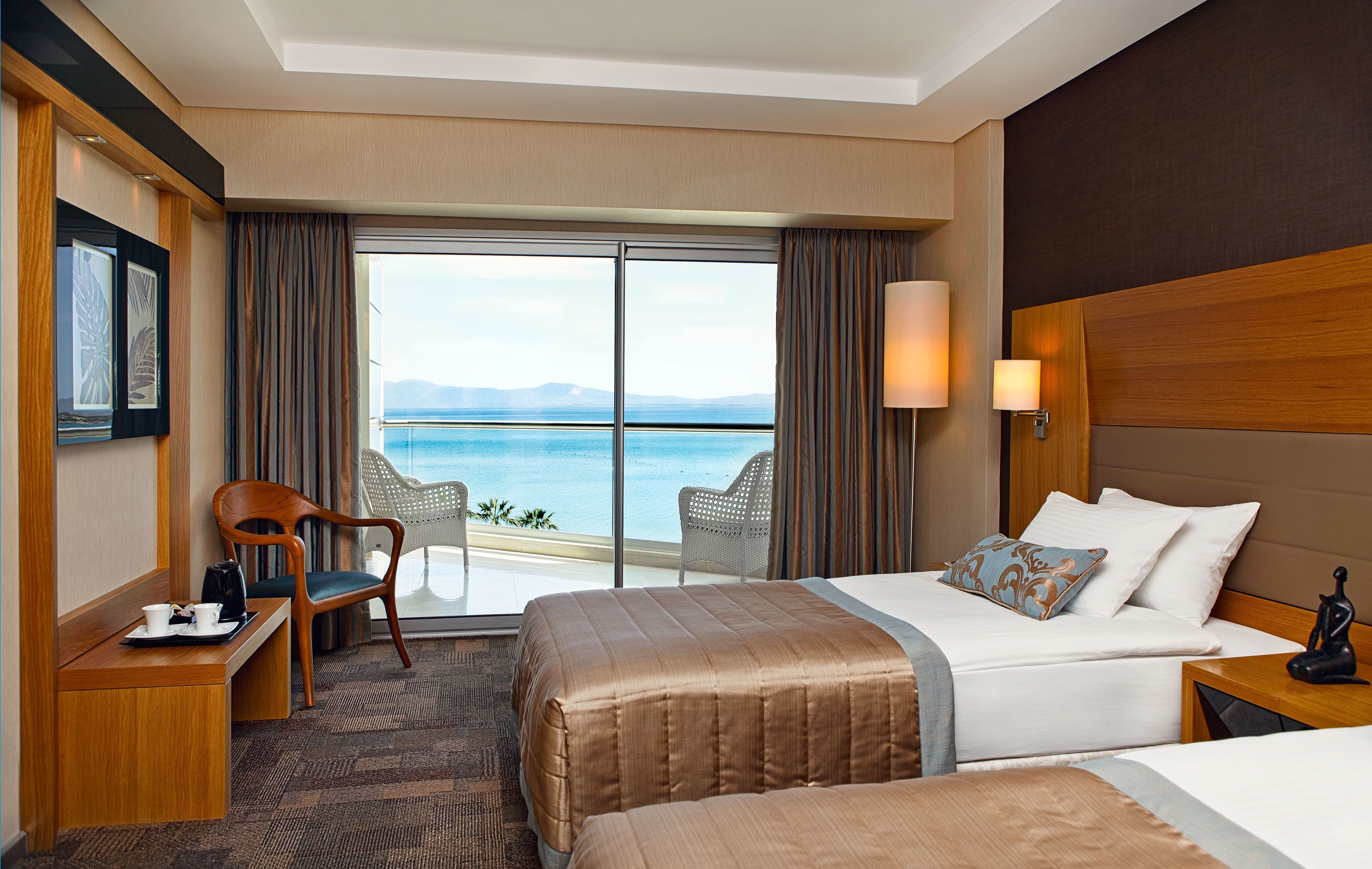 Ein Hotelzimmer mit einem großen Bett, einem Schreibtisch mit Stuhl und Blick aufs Meer.
