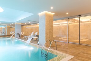 Una piscina techada, una piscina al aire libre, sombrillas