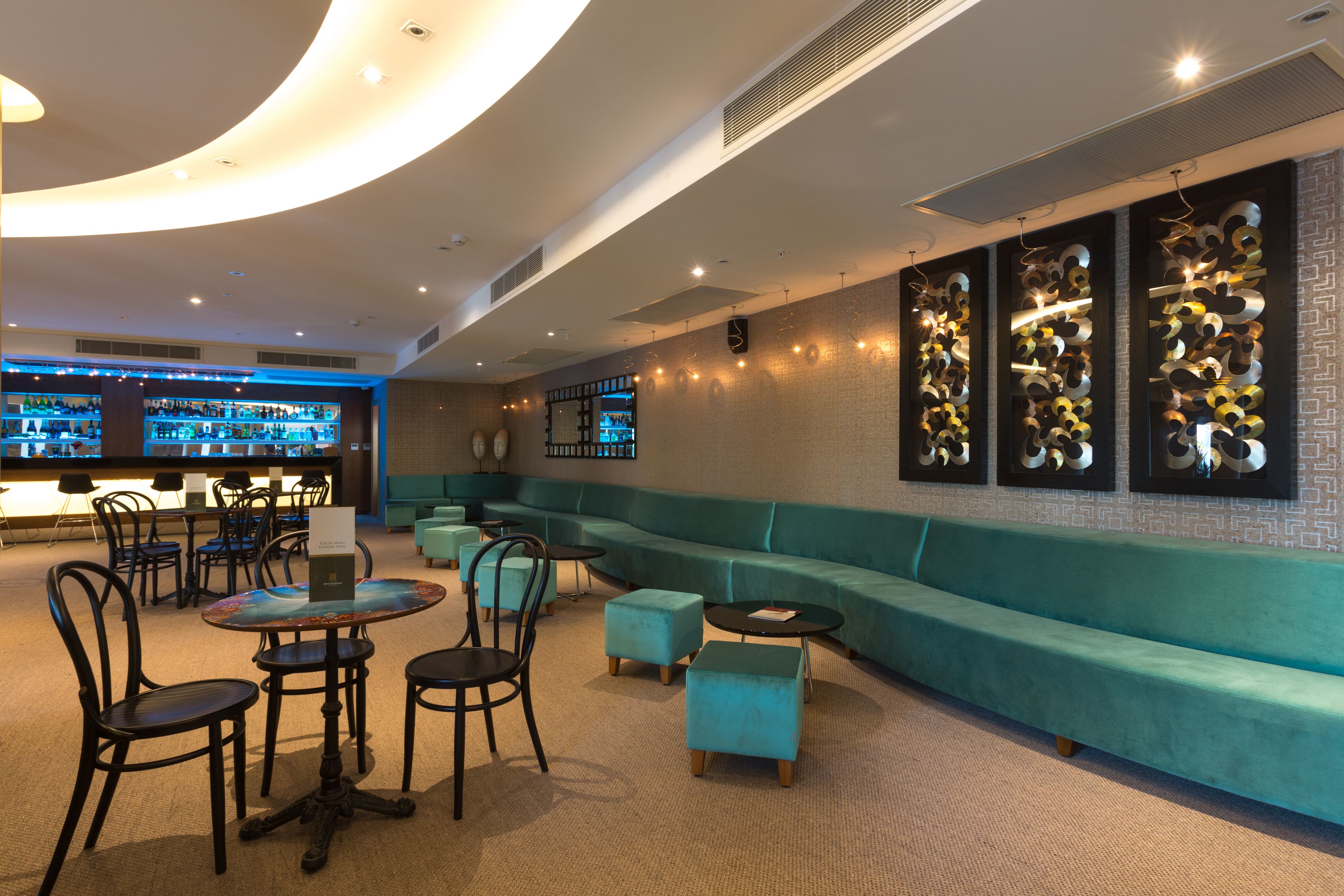 A modern lounge area with a bar, seating, and a decorative wall.
