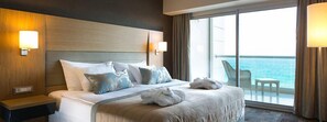 A hotel room with a large bed, two bedside lamps, a view of the sea, and a balcony with a chair and table. - Boyalık Beach Hotel & SPA Thermal Resort  (Cesme)