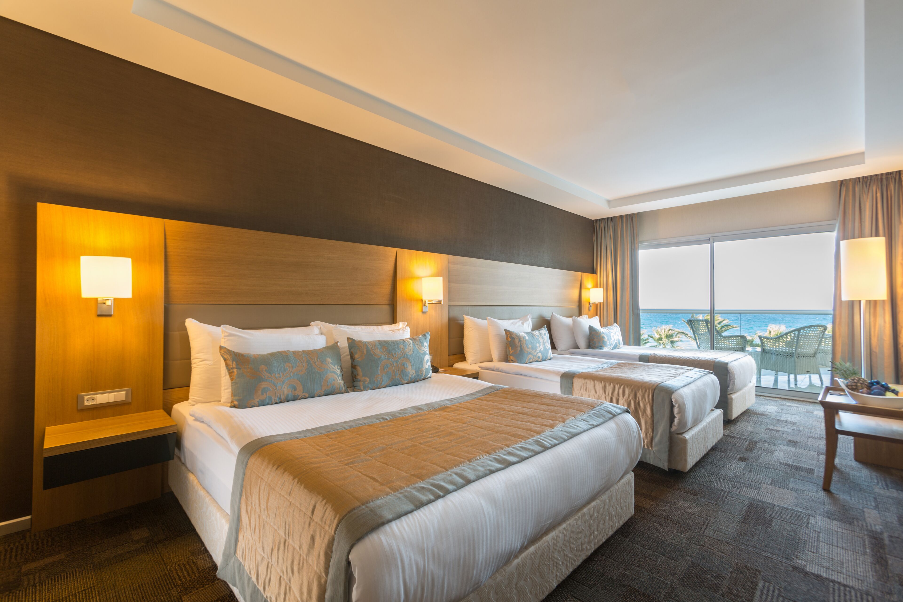 Habitación de hotel con dos camas, una mesita y vista al océano.